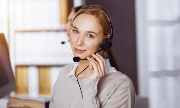 Femme d'affaires parlant par casque dans le bureau. Centre d'appels et divers groupes de personnes en affaires — Photo