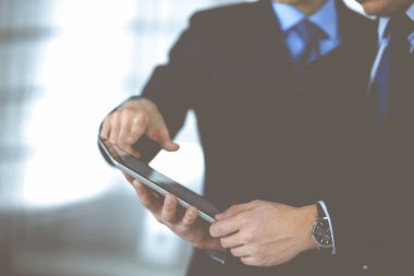 İş adamları yeni projelerini tartışmak için bir tablet bilgisayar kullanıyorlar, modern bir ofiste duruyorlar. İş yerinde iş arkadaşı olan tanınmamış bir iş adamı ya da erkek girişimci. Takım çalışması ve ortaklık