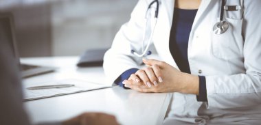 Bilinmeyen kadın-doktor bir klinikteki dolapta yan yana otururken hastasıyla konuşuyor. Steteskopu olan bir kadın doktor, yakın plan. Hastanede mükemmel bir tıbbi hizmet.