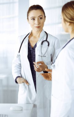 İki kadın doktor klinikte yan yana dururken tıbbi terapiden bahsediyorlar. Doktorlar iş yerinde steteskop kullanır. Tıpta takım çalışması