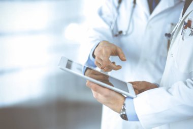 Steteskoplu kimliği belirsiz iki doktor muayene sonuçlarını tartışıyorlar, hastane ofisinde duruyorlar. Doktorlar ilaç kayıtlarını doldurmak için bir bilgisayar tableti kullanıyorlar. Mükemmel tıbbi servis.