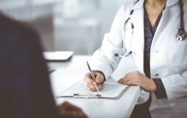 Bilinmeyen kadın-doktor, bir klinikteki dolapta birlikte otururken hastasına bazı tıbbi tavsiyeler yazıyor. Hekim bir dosya kullanıyor, yakın plan. Mükemmel.