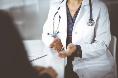 Bilinmeyen kadın-doktor, klinikteki dolapta birlikte otururken hastasıyla teşhisi hakkında konuşuyor. İşyerindeki doktor, yakın plan. Mükemmel bir tıbbi hizmet.