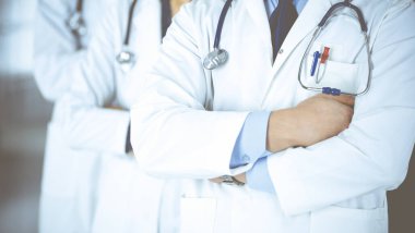 Hastane ofisinde çapraz kolları ve steteskopları olan bir grup modern doktor bir takım gibi duruyor. Doktorlar hastaları muayene etmeye ve yardım etmeye hazır. Tıbbi yardım, sağlık sigortası, en iyi hastalık