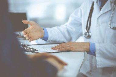 Bir doktor, hastanedeki dolapta birlikte otururken hastasıyla konuşuyor. Doktor ilaç kayıtlarını doldurmak için pano kullanıyor. Mükemmel tıbbi hizmet...