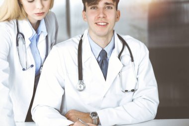 Bir grup genç doktor modern hastane ofisinde hastalık tedavisini tartışıyorlar. Coronavirus dengeleyici, ilaç konseptinde hasta yardımı