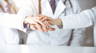 Bir grup modern doktor el ele vererek bir çember oluşturdu. Coronavirus salgını sırasında tıpta takım çalışması, covid 2019