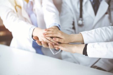 Bir grup modern doktor el ele vererek bir çember oluşturdu. Coronavirus salgını sırasında tıpta takım çalışması, covid 2019