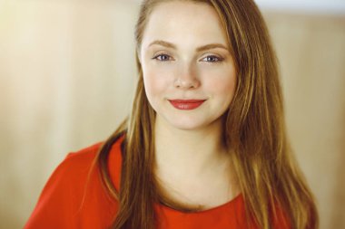 Zeki, kendinden emin, gülümseyen Avrupalı bir kadının resmi. Kollarını kavuşturmuş evde bekliyor.