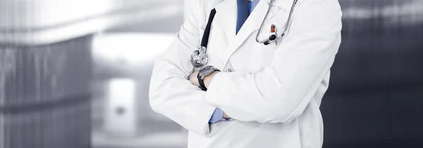 Unbekannter Arzt steht mit verschränkten Armen in Klinik. Medizinkonzept während der Coronavirus-Pandemie — Stockfoto