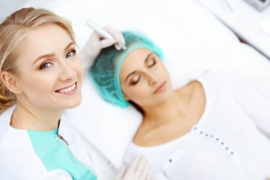 Kadın yüzüne kaş dövmesi yapan profesyonel bir güzellik uzmanı. Güzellik salonunda kalıcı kaş makyajı, yakın çekim. Kozmetoloji tedavisi