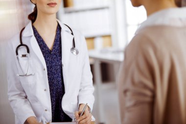 Doktor ve hasta güneşli klinikte otururken sağlık muayenesini tartışıyorlar. Hastanede mükemmel bir tıbbi hizmet.