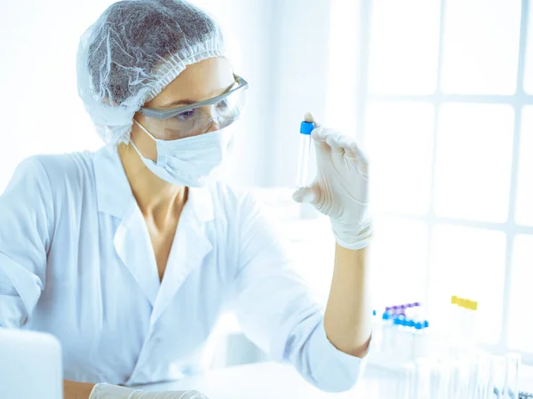 Cientista profissional em óculos de proteção pesquisando tubo com reagentes em laboratório tonificado em azul. Conceitos de medicina e pesquisa científica — Fotografia de Stock