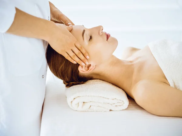 Hermosa mujer disfrutando de masaje facial con los ojos cerrados en el centro de spa — Foto de Stock