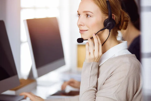 Empresaria hablando por auriculares en la oficina. Centro de llamadas y grupo de personas diversas en los negocios — Foto de Stock