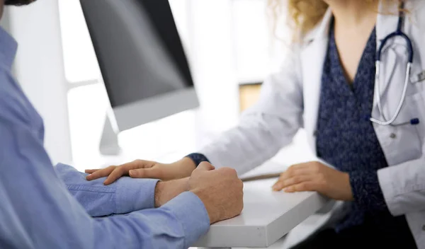 Médico femenino y paciente masculino discutiendo el examen de salud actual mientras está sentado en la clínica, de cerca. Concepto de medicina — Foto de Stock