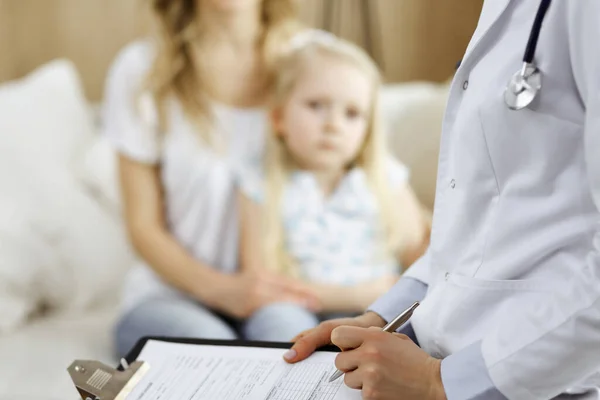 Dokter en patiënt. Kinderarts die klembord gebruikt terwijl ze het kleine meisje onderzoekt met haar moeder thuis. Ziek en ongelukkig kind bij medisch onderzoek. Geneesmiddelenconcept — Stockfoto