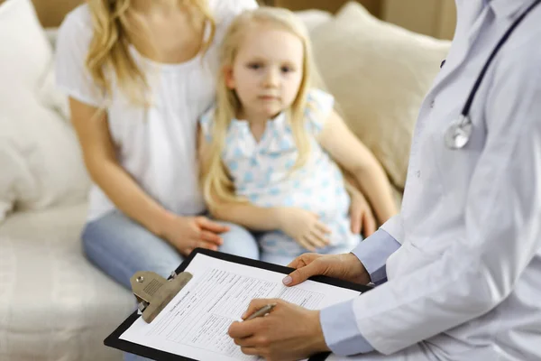 Dokter en patiënt. Kinderarts die klembord gebruikt terwijl ze het kleine meisje onderzoekt met haar moeder thuis. Ziek en ongelukkig kind bij medisch onderzoek. Geneesmiddelenconcept — Stockfoto