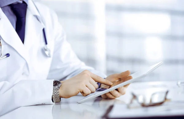 알 수없는 남성 의사가 근무하는 병원에 태블릿 컴퓨터를 가지고 앉아서 일하고 있습니다. 젊은 의사가 일하고 있어요. 완벽 한 의료 서비스, 의학적 개념 — 스톡 사진