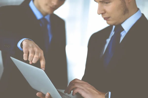 Les gens d'affaires discutent d'une présentation lors d'une réunion, debout dans un bureau moderne. Homme d'affaires inconnu avec un collègue chercher des informations à l'ordinateur portable, avocats à la négociation. Travail d'équipe et — Photo