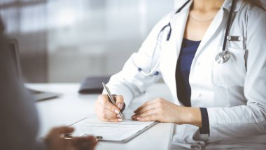 Bilinmeyen kadın doktor, bir klinikteki dolapta otururken hastasına bazı antibiyotikler yazıyor. Steteskoplu kadın doktor panoya yazı yazıyor, kapat