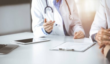 Bilinmeyen erkek doktor güneşli klinikte otururken hasta kadını dinliyor. Coronavirus salgını sırasında ilaç konsepti. Covid 2019