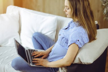 Covid-19 karantinası sırasında dizüstü bilgisayarda çalışan genç bir kadın. Coronavirus salgınında ev konseptinde kal