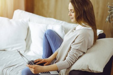 Covid-19 karantinası sırasında dizüstü bilgisayarda çalışan genç bir kadın. Coronavirus salgınında ev konseptinde kal