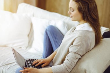 Covid-19 karantinası sırasında dizüstü bilgisayarda çalışan genç bir kadın. Coronavirus salgınında ev konseptinde kal