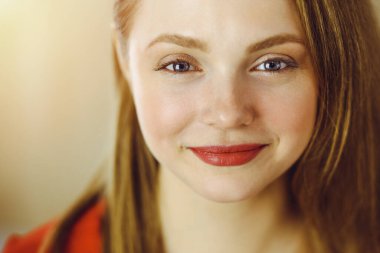 Zeki, kendinden emin, gülümseyen Avrupalı bir kadının resmi. Kollarını kavuşturmuş evde bekliyor.