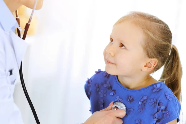 Doktor vyšetřuje malou holčičku stetoskopem. Šťastný usměvavý dětský pacient při běžné lékařské prohlídce. Medicína a zdravotní koncepce — Stock fotografie