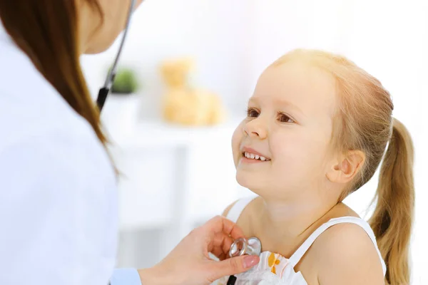 Docteur examinant une petite fille par stéthoscope. Heureux enfant patient souriant à l'inspection médicale habituelle. Médecine et concepts de santé — Photo