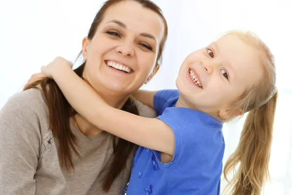 Concept de fête des mères. Enfant fille félicite maman et donne sa carte postale en forme de coeur rouge. Maman et fille heureux souriant et étreignant. Plaisir et vacances en famille — Photo