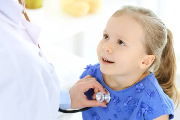 Doutor examinando uma menina por estetoscópio. Paciente de criança sorridente feliz em inspeção médica habitual. Conceitos de medicina e saúde — Fotografia de Stock