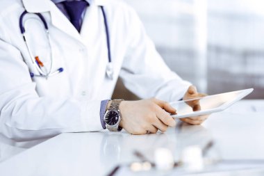 Bilinmeyen erkek doktor klinikteki tablet bilgisayarla yakın planda çalışıyor. İşteki genç doktor. Mükemmel sağlık hizmeti, tıp konsepti
