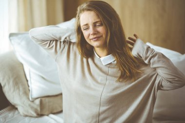 Yorgun bir kadın masaj yapıyor, boynu ağrıyor, kasları geriliyor bilgisayar çalışmalarından dolayı yorgun düşmüş. Coronavirus salgını ve kendini izolasyon karantinası süresince evde kal