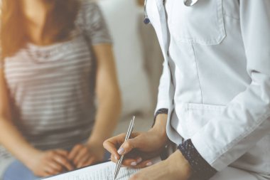 Kadın-doktor ve hasta yakın plan çekimleri. İçeride otururken sağlık muayenesini tartışıyorlar. Coronavirus salgını ve kendini izolasyon karantinası sırasında evde kal. Covid 2019