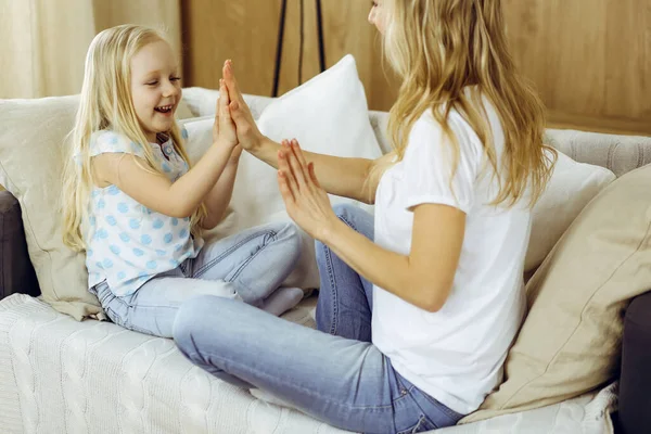 Happy family. Blonde young mother playing and hugging with her cute daughter. Motherhood concept