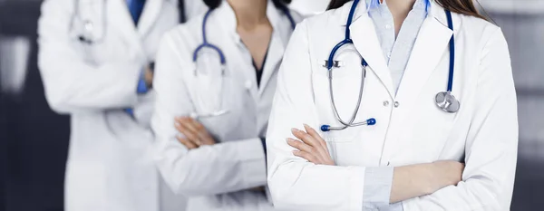 Profesyonel doktorlardan oluşan bir grup klinikte kollarını kavuşturmuş bir takım olarak ayakta duruyor. Coronavirüs salgını sırasında ilaç kavramı — Stok fotoğraf
