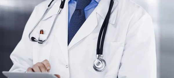 Unbekannter Arzt imitiert Tablet-Computer in seinen Händen, während er in der Klinik steht. Medizinkonzept während der Coronavirus-Pandemie — Stockfoto