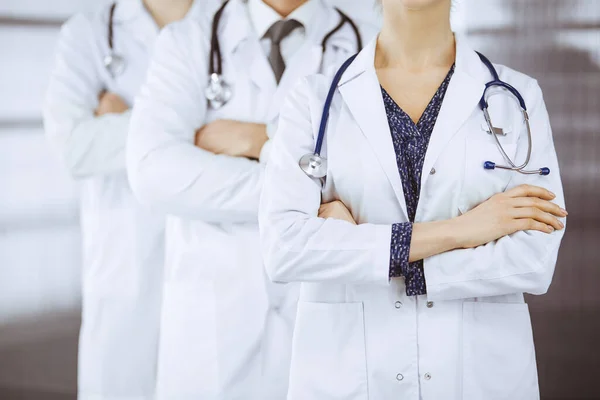 Läkare som står som ett team med armarna korsade på kliniken. Medicinsk hjälp, försäkring och medicin koncept — Stockfoto