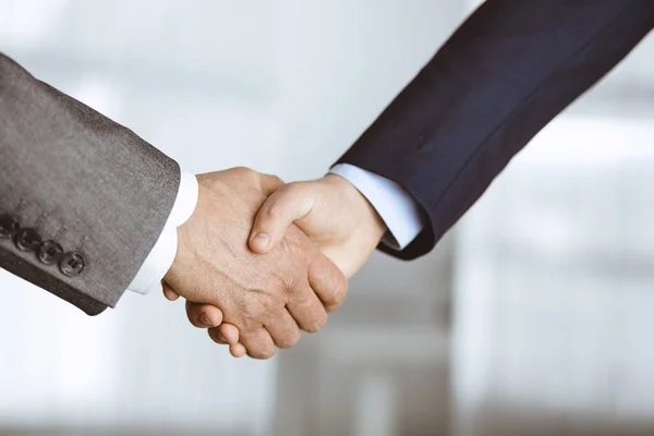 Business people in office suits standing and shaking hands, close-up. Business communication concept. Handshake and marketing