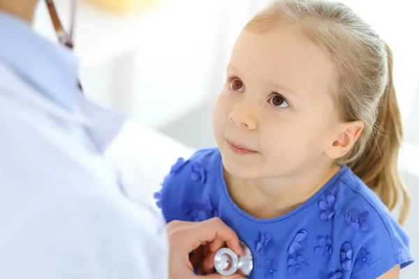 Doctor examinando a una niña por estetoscopio. Feliz niño sonriente paciente en la inspección médica habitual. Medicina y conceptos sanitarios — Foto de Stock
