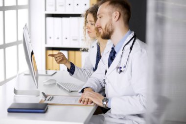 Erkek doktor ve meslektaşı klinikte çalışırken güncel hastalık terapisini tartışıyor. Tıpta takım çalışması