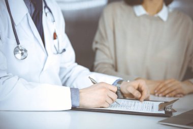 Bilinmeyen erkek doktor ve hasta kadın klinikte oturup dosya kullanırken bir şey tartışıyorlar. Hastanedeki en iyi sağlık hizmeti, ilaç, salgın durdurma.