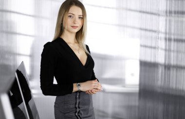 Başarılı genç iş kadını bir şirketin kabinesinde dimdik ayakta duruyor. Ofiste bir sekreterin portresi ya da iş fotoğrafı.