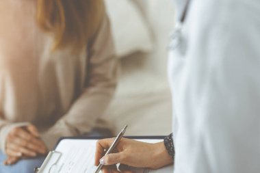 Kadın-doktor ve hasta yakın plan çekimleri. İçeride otururken sağlık muayenesini tartışıyorlar. Coronavirus salgını ve kendini izolasyon karantinası sırasında evde kal. Covid 2019