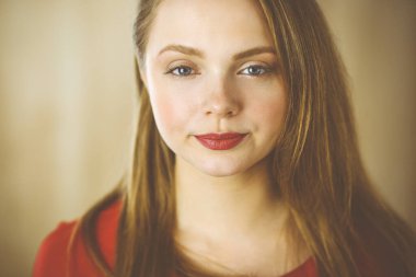 Zeki, kendinden emin, gülümseyen, Avrupalı bir kadının kollarını kavuşturup evinde dikilirken çekilmiş bir fotoğrafı. Çekici genç kız öğrenci serbest çalışan, kırmızı giyinmiş, kameraya bakıyor.