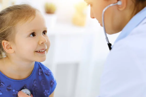 닥터가 청진기로 어린 소녀를 진찰하고 있어. 평상시의 진료 에서 미소짓는 어린이 환자에게 행복 한 미소를 짓는다. 의학 과 의료 개념 — 스톡 사진