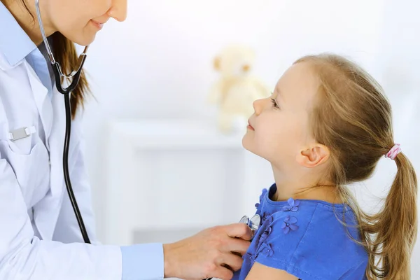 Doctor examinando a una niña por estetoscopio. Feliz niño sonriente paciente en la inspección médica habitual. Medicina y conceptos sanitarios —  Fotos de Stock